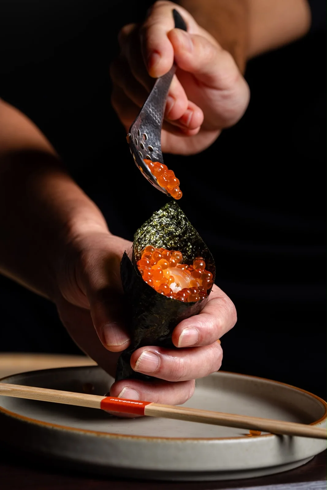 Hand roll being topped with roe